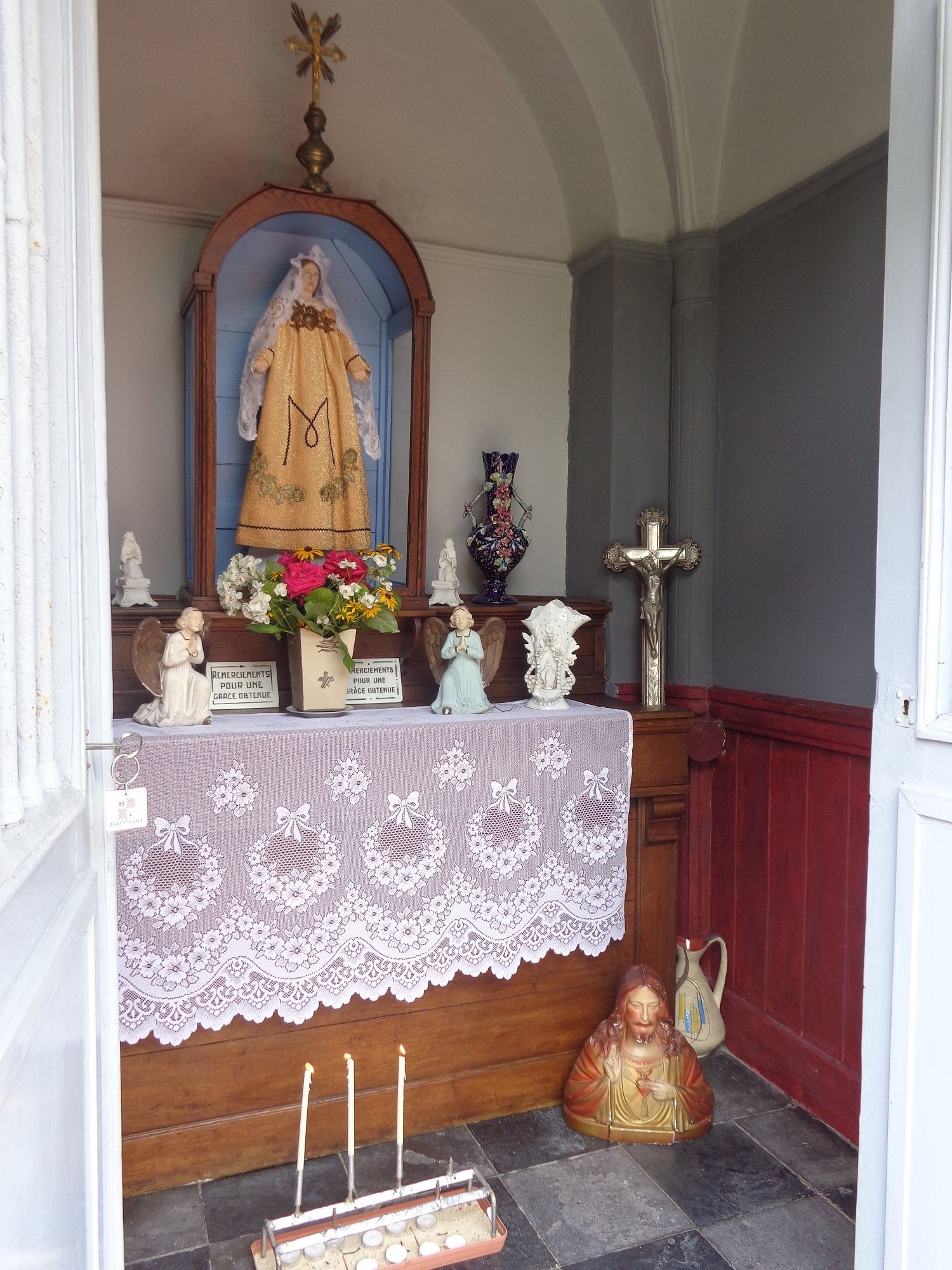 L'intérieur vu depuis la porte : la statue, les fleurs et des bougies allumées.