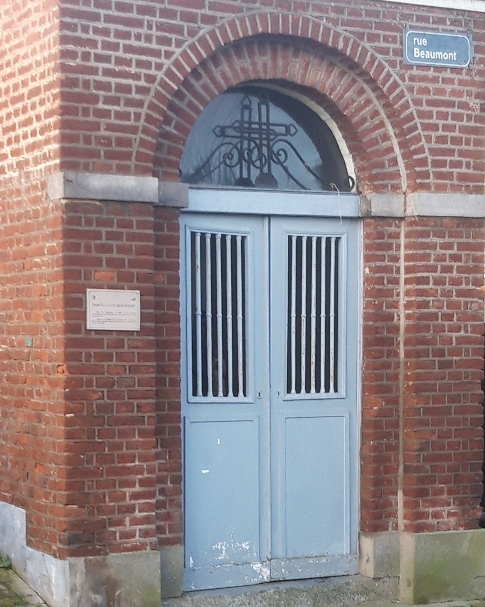 La porte bleue à deux battants, avec ses barreaux ; la peinture du bas s'en va.