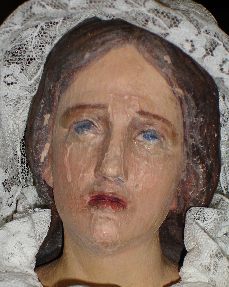 Le visage peint de la statue de Notre-Dame des Sept Douleurs ; la peinture se fissure et s'écaille.
